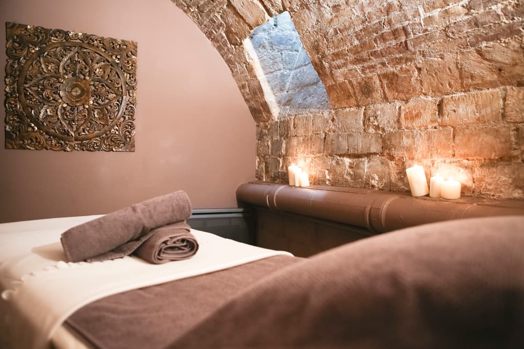 Salle de soins sous une voûte de pierre, table préparée, sans personne.