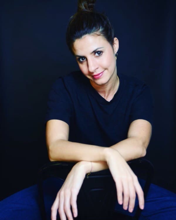 Portrait d’Elisa Willet, assise, les bras croisés sur le dossier d’une chaise.